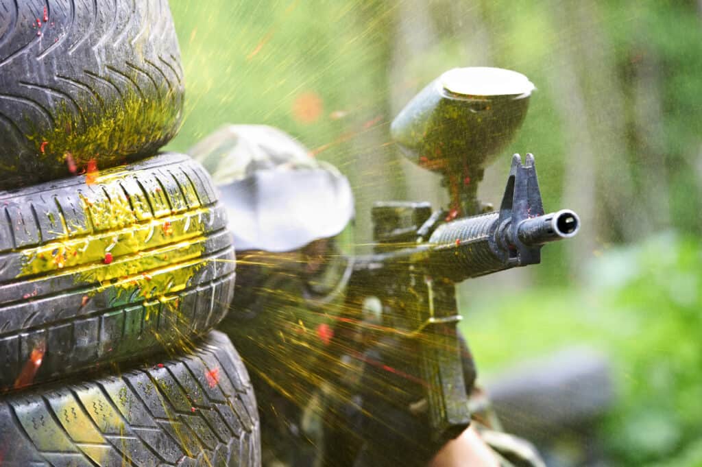 Paintball player taking cover during a game and action filled retirement hobby