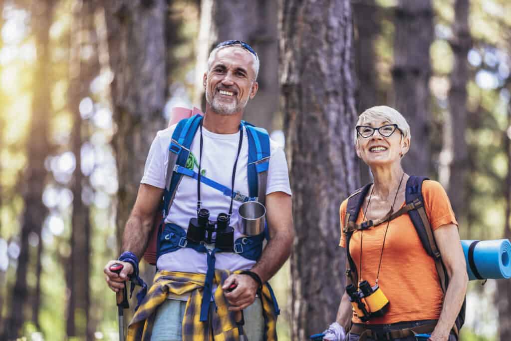 an active retired couple hiking through the woods.