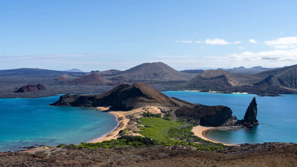An aerial view of Bartolome island and the Pinnacle rock with Santiago Island in the background - Galapagos Islands