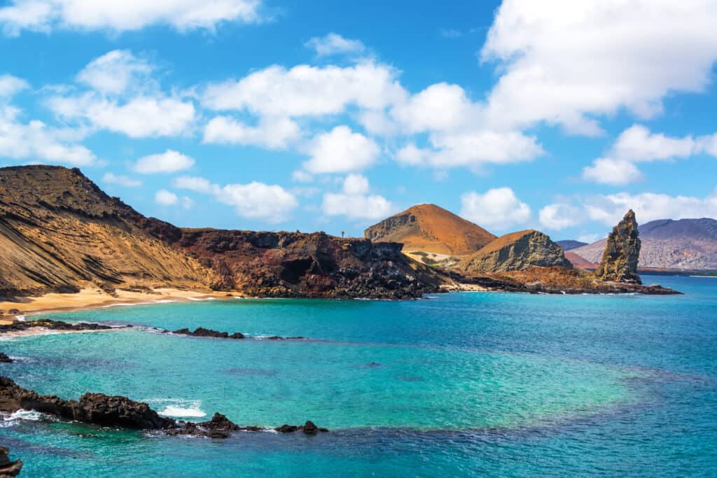 View of an underwater crater in the foreground with Pinnacle Rock in the background on Bartolome Island in the Galapagos Islands, part of a great tour for seniors