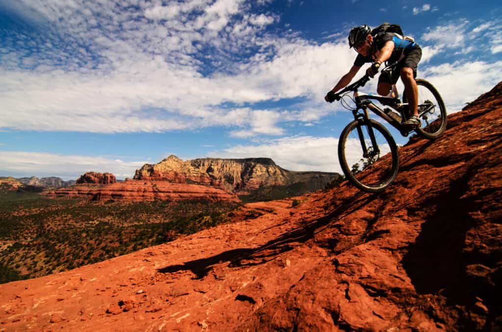 Mountain biking down Slickrock Mountain in Sedona Arizona. Bike tour over red rock part of an Sedona tour for active seniors.