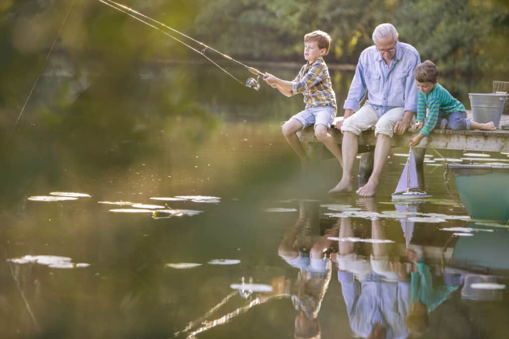 vacationing with grandparents, a grandfather fishing with his two young grandsons on the dock