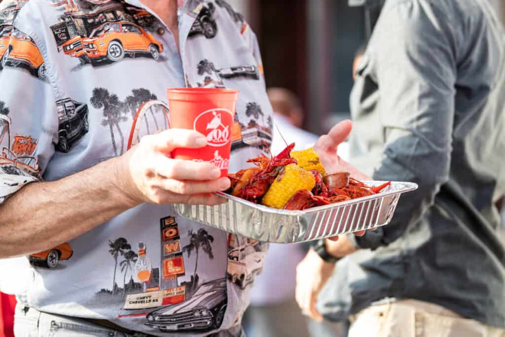 New Orleans, USA - April 23, 2018: Old town in Louisiana city with people by 700 club restaurant eating seafood lobsters holding trays