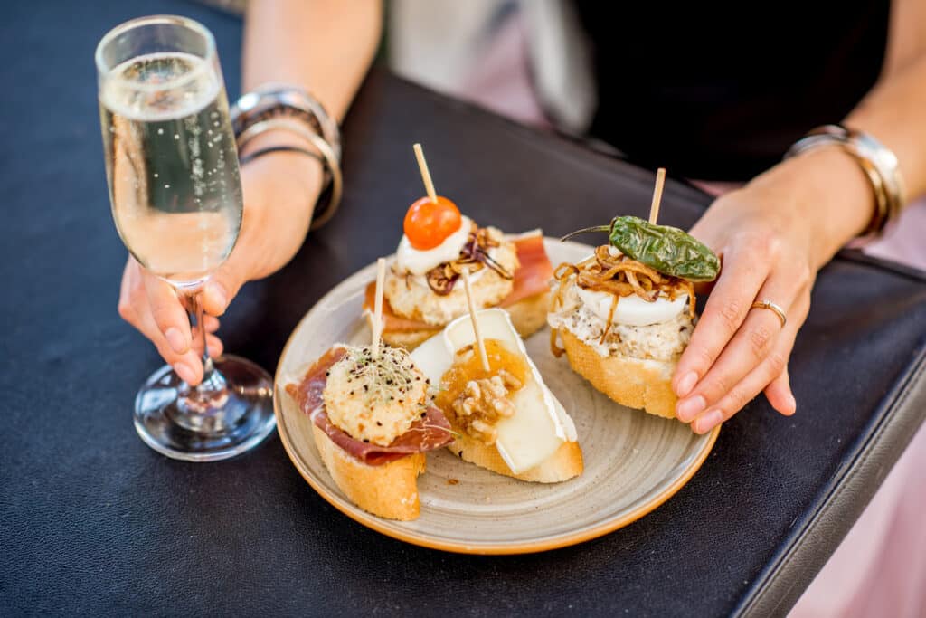 Beautiful and colorful set of pinchos, traditional spanish snack related to tapas, with glass of wine outdoors on the table. No Food and win foodie tour would be complete without tapas!