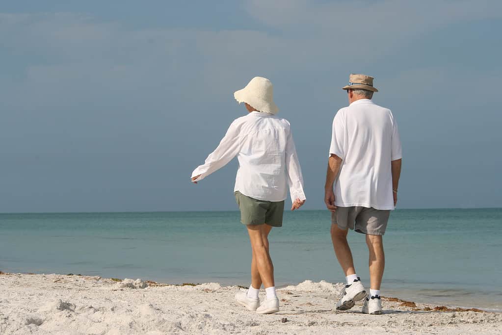 Active older couple walking the beach in Florida. Cover picture for the post - the Best Florida Tours for Active Seniors: A Guide