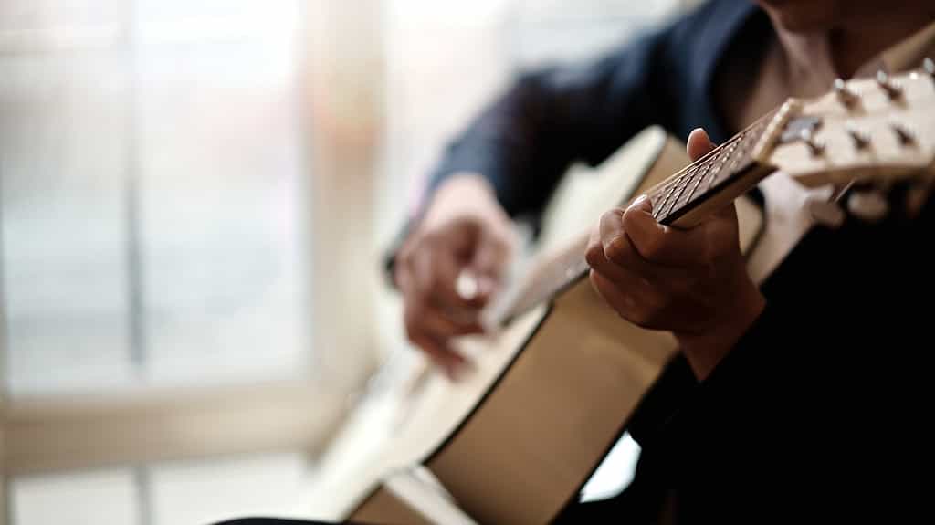 Cropped shot of man practicing in playing acoustic guitar, a great indoor hobby for retired men