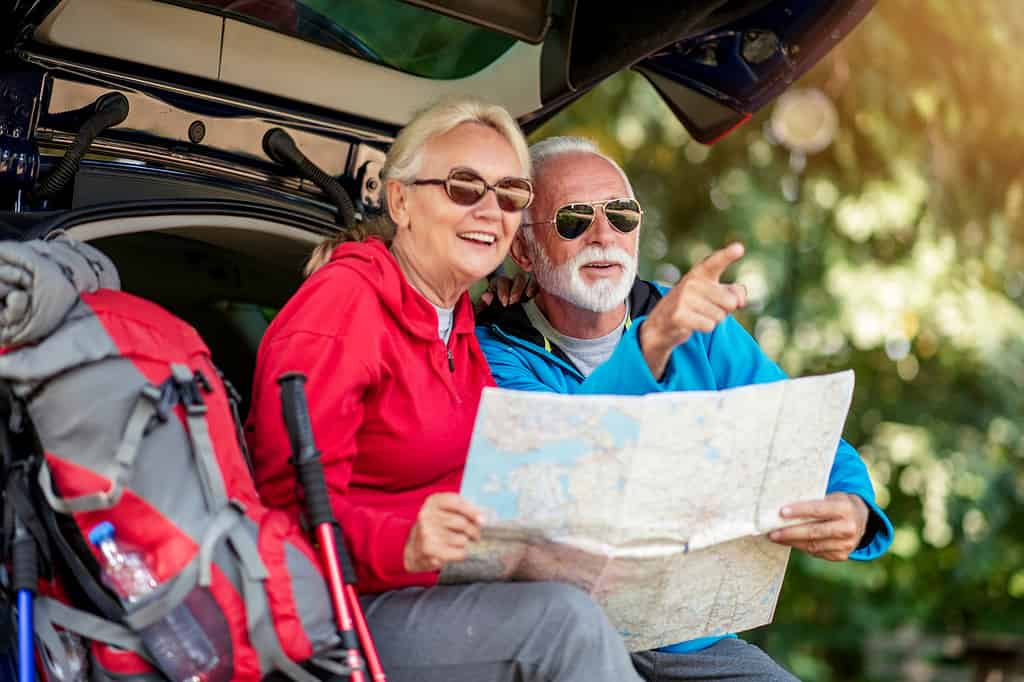 mountain climbing is one of the many hobbies that allows you to travel the world, this older couple has their packs, poles, and map all ready to go!