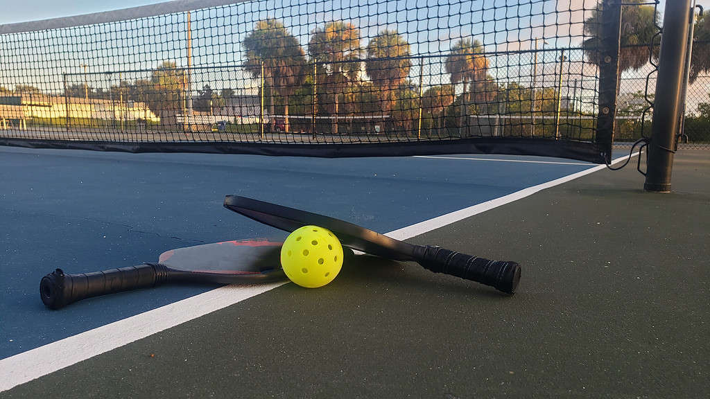 Pickleball paddles and a ball low angle on an empty outdoors court at a public park in St. Petersburg, Florida.