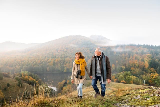 Retired couple walking outdoors in a mountainous area in the fall