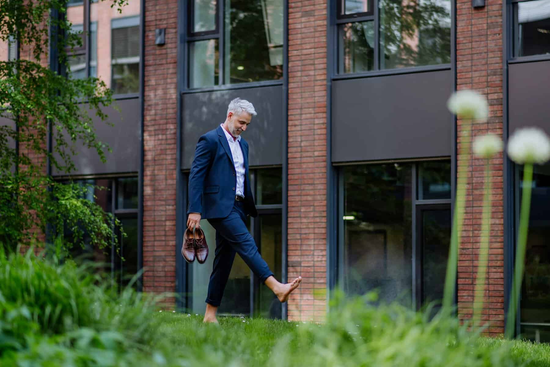barefoot man in a suit walking on the grass I miss work I don't miss working